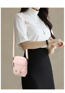 Detail of pink vintage motorcycle crossbody bag with metallic studs and long woven tassels