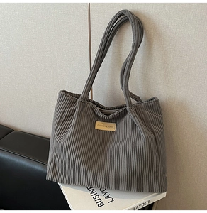 Détail du sac cabas en velours côtelé gris foncé avec patch en cuir et texture côtelée