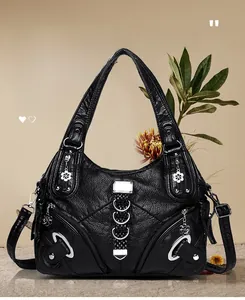 Close-up of black lychee texture leather bag with silver rings and flower zipper pulls