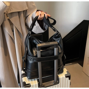 Detailansicht einer schwarzen Reisetasche mit Trolley-Schlaufe auf einem Koffer