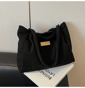 Gros plan sur la texture en velours côtelé noir du sac cabas avec étiquette en cuir