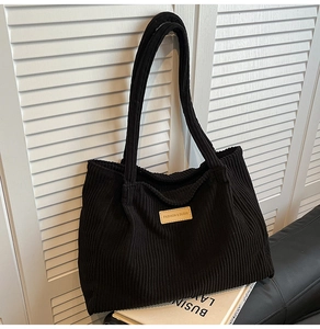 Détail du cabas en velours côtelé noir avec écusson en cuir et texture côtelée douce