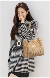 Detail of khaki corduroy tote bag with chain strap and woven brand tag shown on model