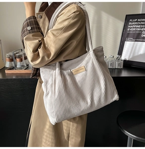 Gros plan du sac cabas en velours côtelé beige montrant la texture et l'écusson en cuir
