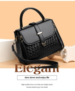Detail of black woven leather handbag with gold metal clasp on a stylish pedestal