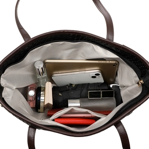 Large black woven tote bag with brown handles showing spacious interior with personal items