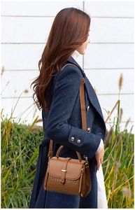 Detail view of brown crocodile texture on luxury tote bag in outdoor lifestyle setting