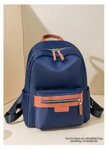 Detail of dark blue nylon backpack featuring brown leather handles and multi-way straps