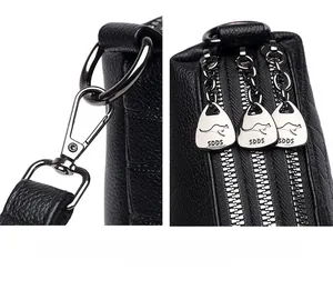 Detail of black lychee leather bag with three zippers and dark metal hardware hook