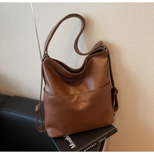 Détail d'un grand sac bandoulière marron en cuir avec texture grainée et poche frontale