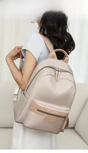 Model wearing a large beige nylon travel backpack in a minimalist indoor setting