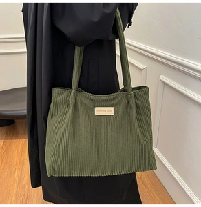 Detail of olive green corduroy tote bag featuring a leather patch and wide straps