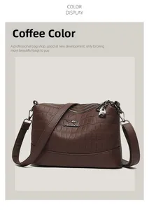 Detail of coffee brown crossbody bag showing crocodile texture and brand logo zippers