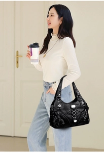 Detailed view of black pebbled leather tote with silver zippers and floral metal charm