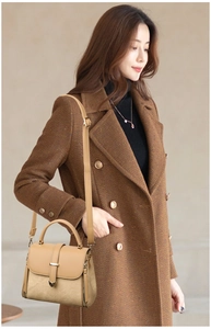 Detail of light beige crossbody bag with metal buckle on woman in brown coat