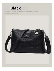 Close-up of black crocodile pattern leather bag with dual gold zippers and metal logo