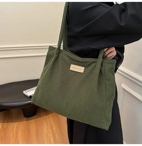 Detail shot of a dark green corduroy tote bag showing large capacity and textured fabric