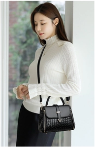 Detailed view of black structured handbag with smooth leather and woven texture mix