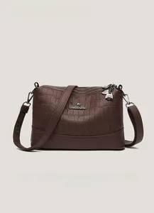 Detail of dark brown faux crocodile leather bag with triple zippers and metal logo