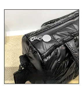 Detail view of smooth silver zipper on a black quilted shiny puffer crossbody bag