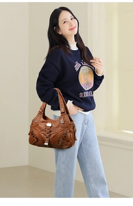 Brown leather handbag with woven texture and metal ring details shown on model