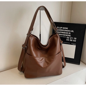 Gros plan d'un sac cabas vintage en cuir souple marron avec texture grainée et sangle
