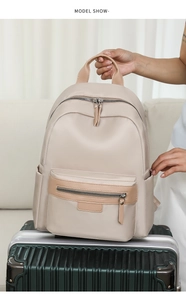 Detail of a beige nylon travel backpack with leather accents placed on a suitcase handle