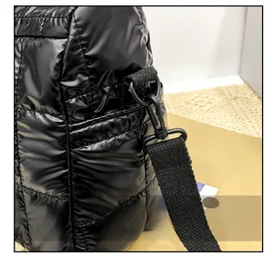Detailed view of the black puffer bag featuring quilted fabric and metal strap hooks