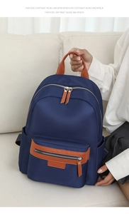Detail of blue nylon backpack with contrast brown faux leather handles and zip pulls