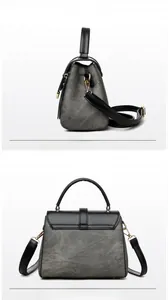 Detail view of grey textured crossbody bag with black leather flap and gold hardware