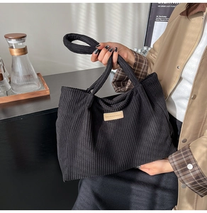 Gros plan d'un cabas en velours côtelé noir avec un écusson en cuir et lettrage embossé