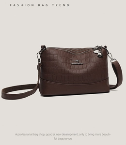 Detail of three-zipper dark brown crossbody bag with crocodile texture and logo