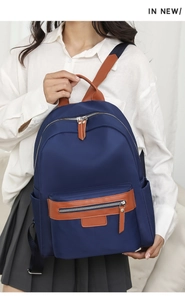 Detail showing navy nylon travel backpack with brown leather handle and metal zipper