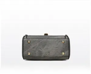 Detailed view of the handbag bottom featuring four gold protective metal feet and texture