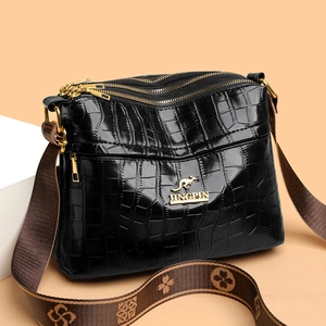 Black crocodile embossed crossbody bag with multi-layer zippers and patterned strap