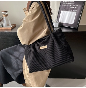 Vue détaillée du sac cabas en velours côtelé noir avec texture rainurée et écusson