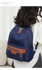 Deep blue nylon backpack featuring brown leather zipper pulls and high-density waterproof fabric