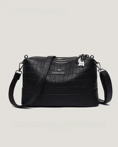 Detail of black crocodile texture faux leather bag with metallic kangaroo logo and zippers