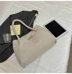 Detail shot of cream corduroy tote bag showing ribbed texture and brown logo patch