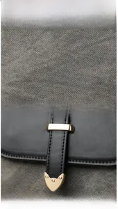 Detail of woven fabric texture and gold shield hardware on a vintage crossbody handbag