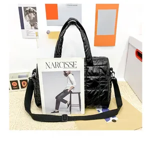 Close-up of a large black quilted puffer tote bag with a magazine showing its spacious capacity