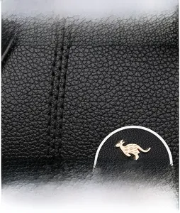 Detail von schwarzem Leder mit Lychee-Maserung, goldenem Känguru-Logo und verstärkter Naht