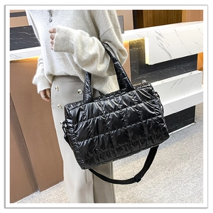 Detail of black quilted puffer tote bag featuring glossy finish and adjustable strap