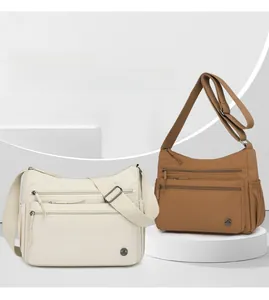 Detail of multi-pocket nylon crossbody bags in beige and tan with adjustable straps