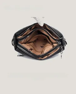 Detailed macro view of the three zipper compartments and textured lychee leather bag