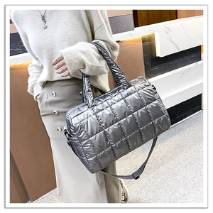 Detail of silver metallic quilted tote bag with dual handles and adjustable shoulder strap