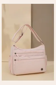 Detail of light pink nylon shoulder bag showing multiple front zipper pockets and strap