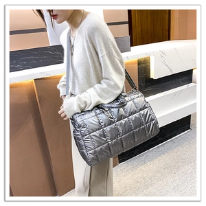 Silver quilted puffer tote bag with metallic finish and wide shoulder strap on model
