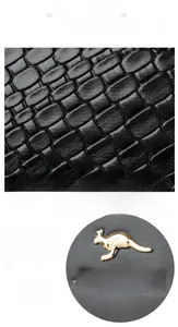 Détails de la texture similicuir noir à motif croco et logo kangourou doré du sac