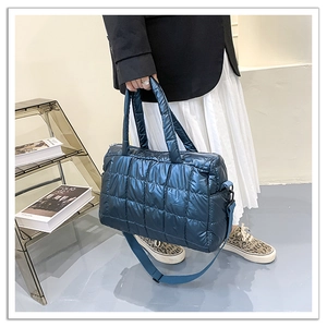 Close-up of blue quilted puffer tote bag with metallic glossy finish and nylon strap